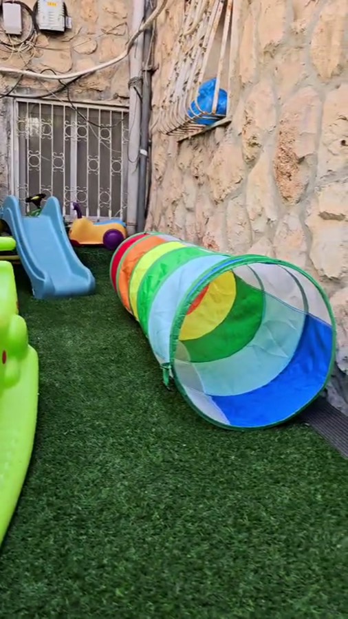 החצר — דשא סינתטי, מגלשה, מנהרת משחק וצעצועי רכיבה